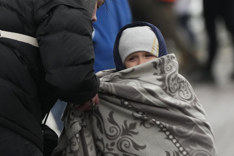 A woman covers her son with a blanket after fleeing the war from neighboring Ukraine at the border crossing in Medyka, southeastern Poland, Sunday, April 3, 2022. (AP Photo/Sergei Grits)
