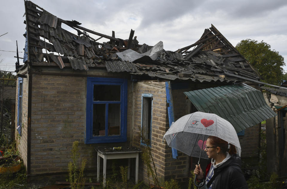 Local resident Ekaterina, 22, stands next to her residential building that was damaged after an overnight Russian attack in Kramatorsk, Ukraine, Tuesday, Oct. 4, 2022. (AP Photo/Andriy Andriyenko)