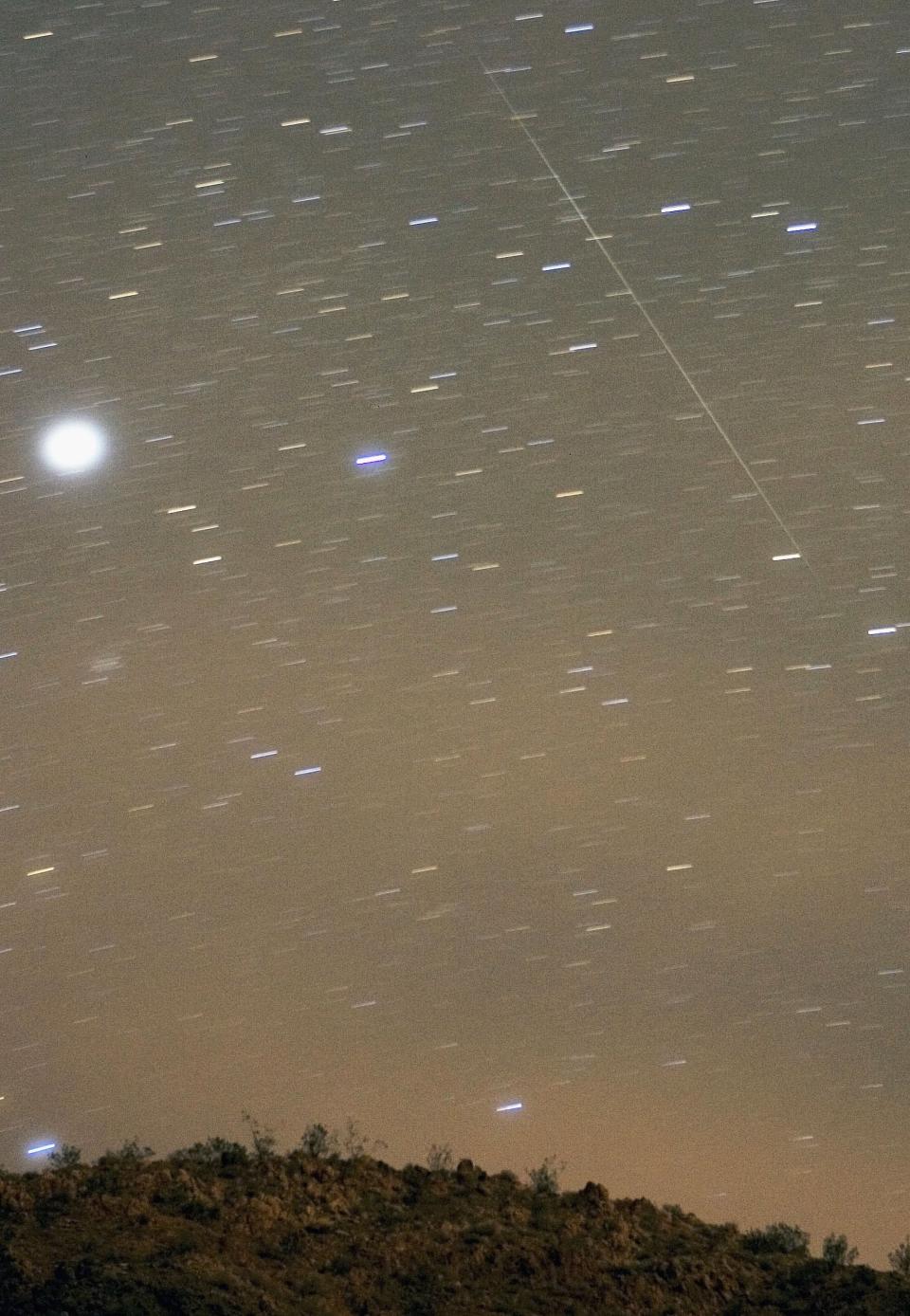 A Geminid meteor streaks diagonally across the sky against a field of star trails in this two-minute exposure early December 14, 2006 over the Lake Mead National Recreation Area near Willow Beach, Arizona. The meteor display, known as the Geminid meteor shower because it appears to radiate from near the star Castor in the constellation Gemini, is thought to be the result of debris cast off from an asteroid-like object called 3200 Phaethon. The shower is visible every December. (Photo by Ethan Miller/Getty Images)