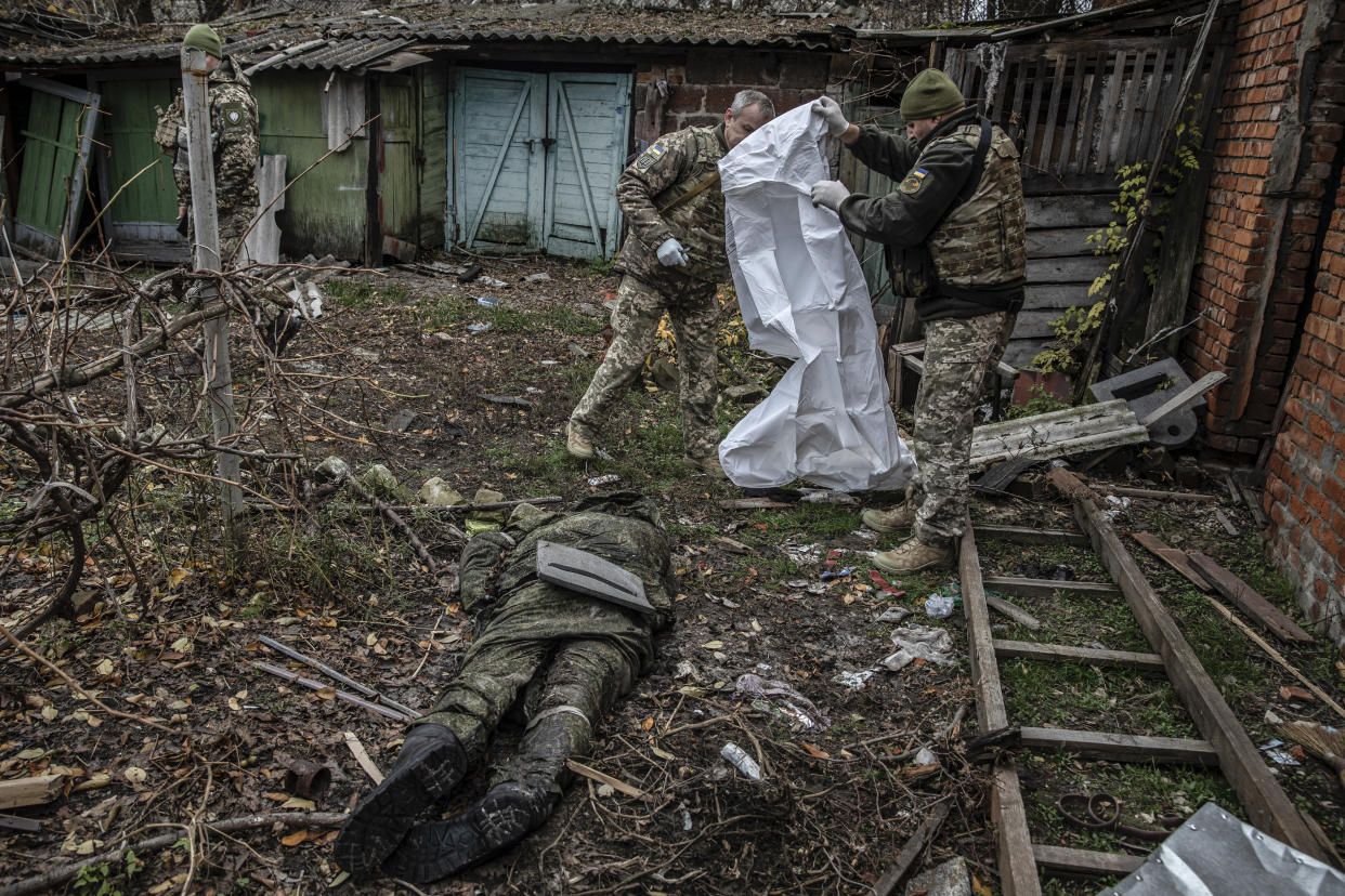 Miembros de las Fuerzas Armadas ucranianas retiran el cuerpo de un militar ruso en Kupiansk-Vuzlovyi, cerca de la línea fronteriza en la región noreste de Járkov en Ucrania, el 1 de noviembre de 2022. (Finbarr O'Reilly/The New York Times)