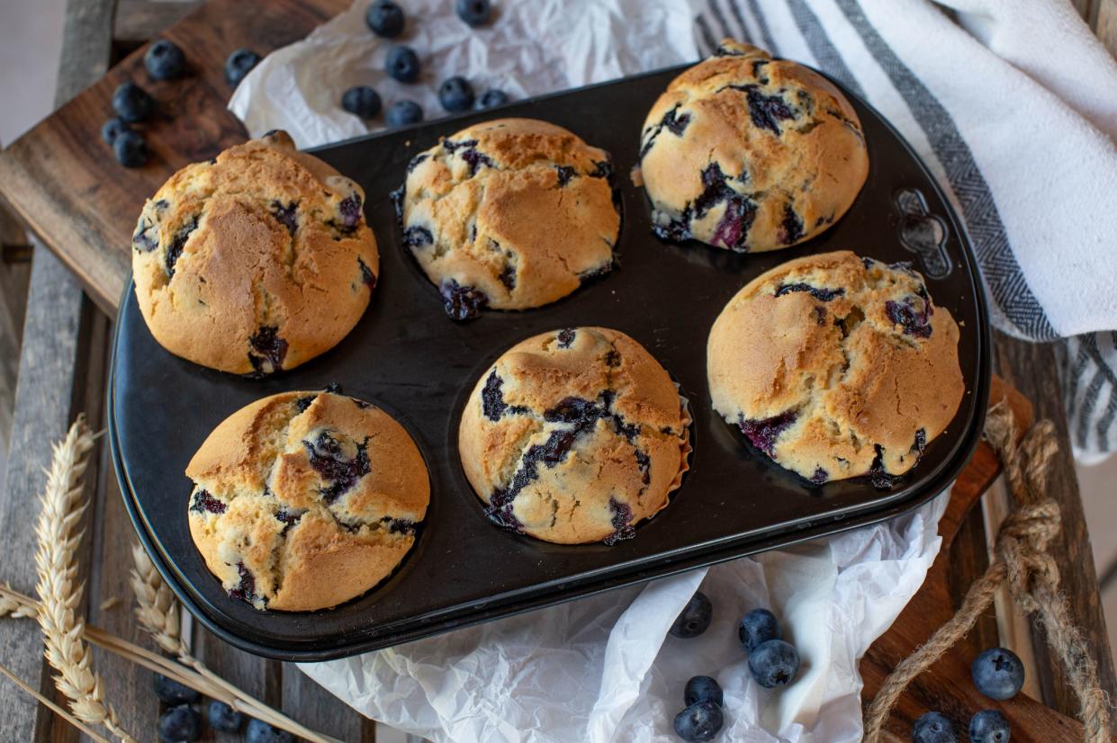 Fresh and homemade baked blueberry muffins. Served hot in a baking pan on wooden background