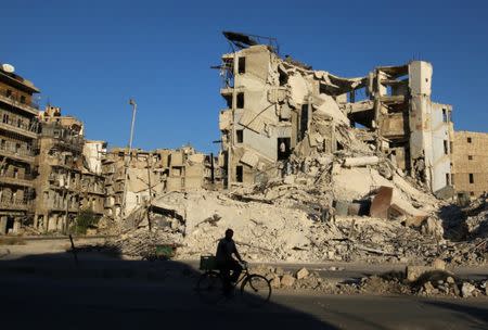 A man rides a bicycle past damaged buildings in the rebel-held Tariq al-Bab neighborhood of Aleppo, Syria, September 26, 2016. REUTERS/Abdalrhman Ismail
