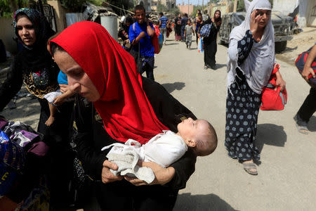 A displaced Iraqi woman who fled from clashes, carries her baby in western Mosul, Iraq, June 3, 2017. REUTERS/Alaa Al-Marjani