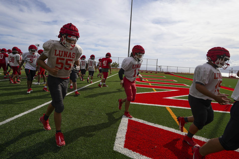Lahainaluna high school football team members run back to the field at Sue D. Cooley Stadium during their first week returning to practice on campus after August's wildfire Tuesday, Oct. 10, 2023, in Lahaina, Hawaii. (AP Photo/Mengshin Lin)