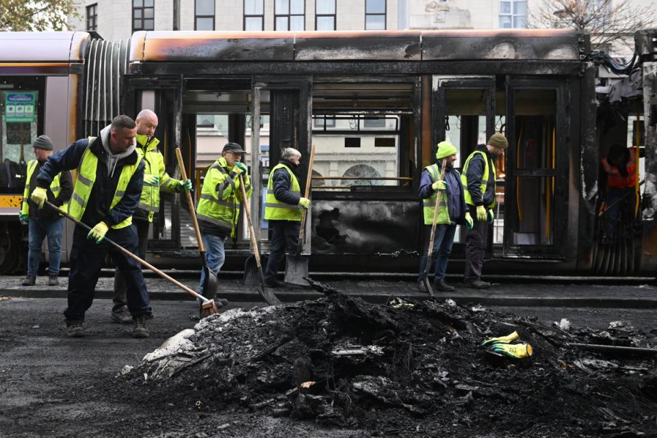 Workers clean up the debris of a burnt train on Friday in the wake of the riots in Dublin, Ireland (Getty Images)