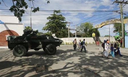 Residents walk past a government military vehicle as they evacuate near an area where members of Muslim rebels Moro National Liberation Front (MNLF) have occupied in Zamboanga city, southern Philippines September 9, 2013. REUTERS/Stringer