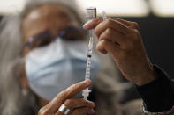 Dr. Manjul Shukla transfers Pfizer COVID-19 vaccine into a syringe, Thursday, Dec. 2, 2021, at a mobile vaccination clinic in Worcester, Mass. As the U.S. recorded its first confirmed case of the omicron variant, doctors across the country are experiencing a more imminent crisis with a delta variant that is sending record numbers of people to the hospital in New England and the Midwest. (AP Photo/Steven Senne)