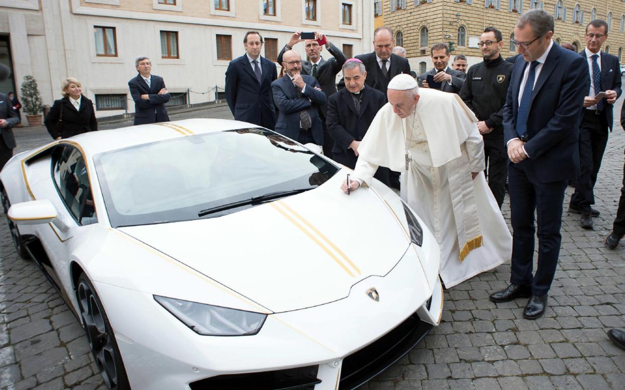 The Pope with a Lamborghini in the Vatican colours of white and yellow, which he was gifted in 2018 and had sold at auction for charity - AP