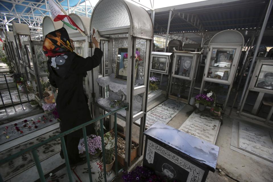 An Iranian woman cleans decoration of the grave of his brother who was killed during 1980-88 Iran-Iraq war, at the Behesht-e-Zahra cemetery just outside Tehran, Iran, Thursday, March 20 2014, on the eve of the Iranian New Year, or Nowruz. Nowruz which means "New Day" in Persian, marks the first day of spring and the beginning of the year on the Iranian calendar, which occurs exactly on the Spring Equinox, and usually begins on March 21 or the previous or following day. (AP Photo/Vahid Salemi)