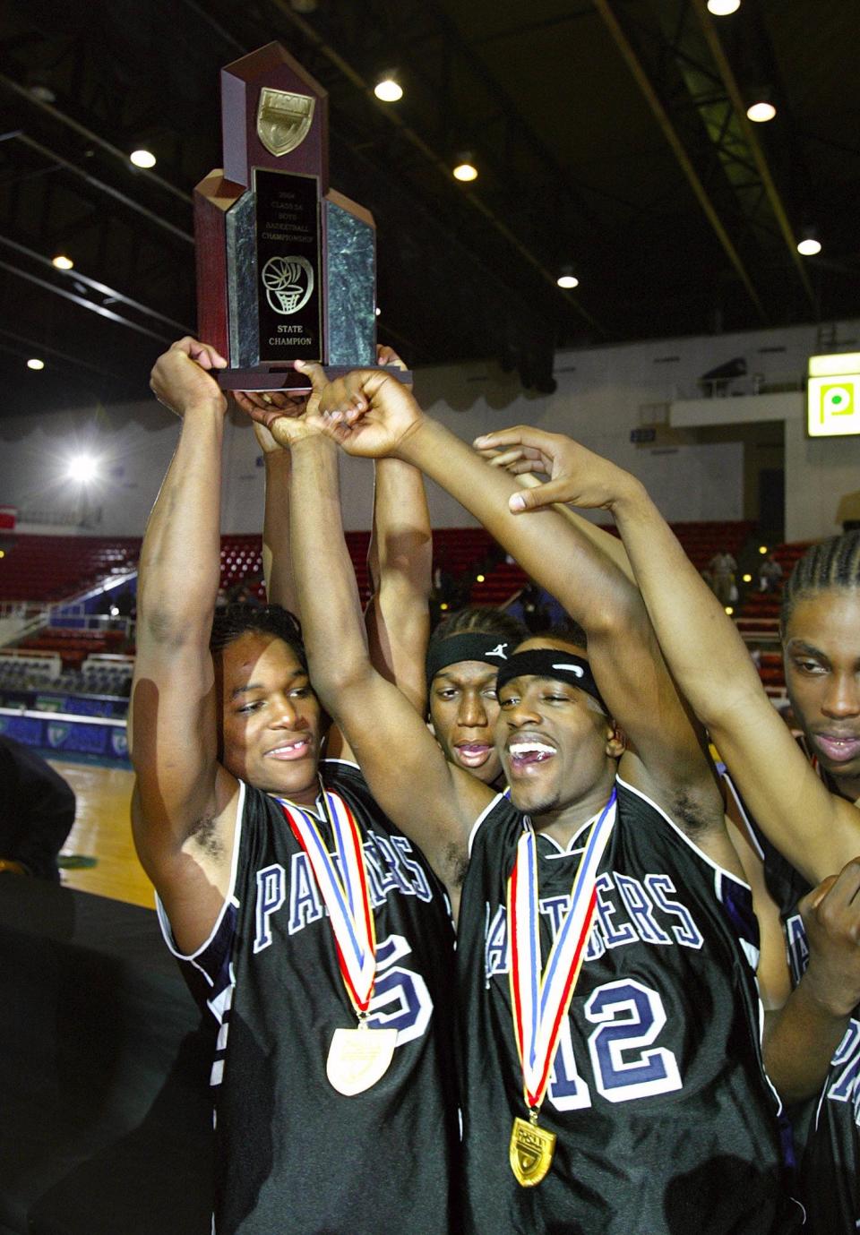 Dwyer Panthers Corey Young, left, and Leemire Goldwire, right, hoist the state championship trophy  after defeating the Lake Howell Silver Hawks during the Boys Class 5A FHSAA State Championship game at the Lakeland Center  in Lakeland . Friday, March 12, 2004.