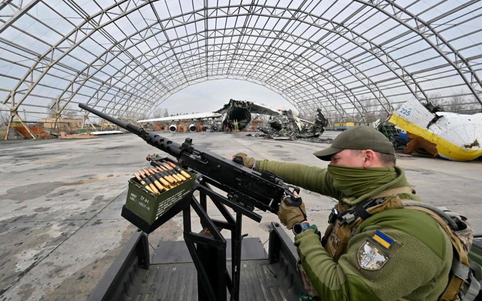 A Ukrainian serviceman checks a machine gun in front of a destroyed Ukrainian Antonov An-225 "Mriya", the largest cargo aircraft in the world, at an aerodrome in in Hostomel, during a donation ceremony of some ten off-road vehicles mounted with machine guns, from volunteers project HEROCAR for mobile fire groups of air defense to resist drones attacks, on April 1, 2023, amid the Russian invasion of Ukraine. (Photo by Sergei SUPINSKY / AFP) (Photo by SERGEI SUPINSKY/AFP via Getty Images) - SERGEI SUPINSKY/AFP via Getty Images