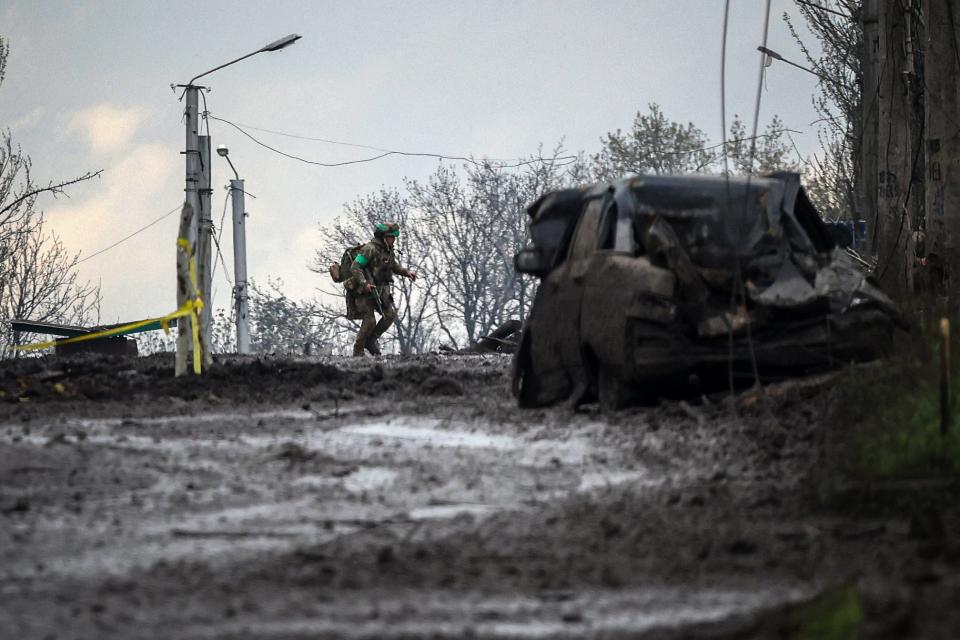 A Ukrainian serviceman runs for cover from shelling across a street in the frontline town of Bakhmut, Donetsk region on  23April 2023 (AFP via Getty Images)