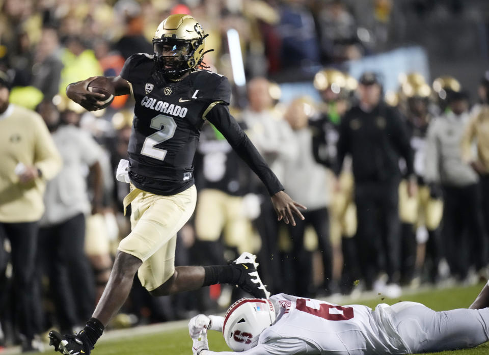 Colorado quarterback Shedeur Sanders, left, runs away from Stanford cornerback Collin Wright during the first half of an NCAA college football game Friday, Oct. 13, 2023, in Boulder, Colo. (AP Photo/David Zalubowski)