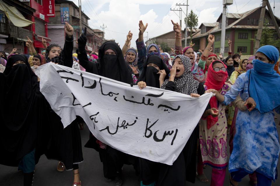 FILE - In this Friday, Aug. 9, 2019, file photo, Kashmiri women hold a banner that reads: "This country is ours and we will decide its future," during a protest march in Srinagar, Indian controlled Kashmir. India on Thursday, Oct. 31, 2019, formally implemented legislation approved by its Parliament in early August that removes Indian-controlled Kashmir's semi-autonomous status and begins direct federal rule of the disputed area amid a harsh security lockdown and widespread public disenchantment. (AP Photo/Dar Yasin, File)