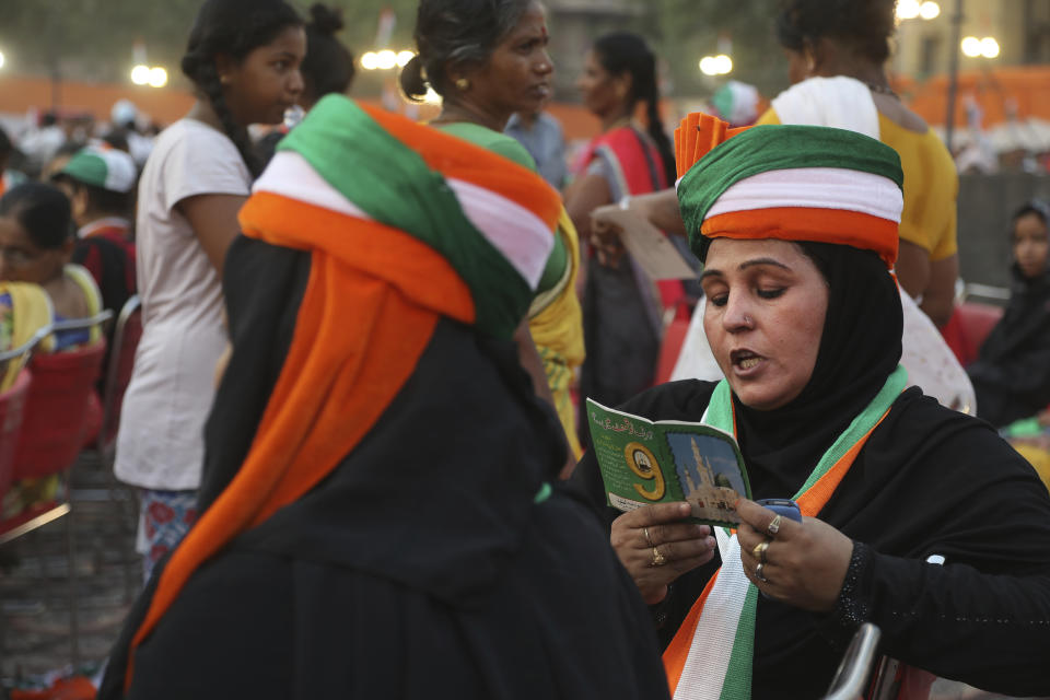 FILE - In this Thursday, May 9, 2019 file photo, a Congress party supporter reads verses from the Quran as she waits for the arrival of party president Rahul Gandhi for an election campaign rally in New Delhi, India. The final phase of India’s marathon general election will be held on Sunday, May 19. The first of the election’s seven staggered phases was held on April 11. Vote counting is scheduled to start on May 23. India has 900 million eligible voters. (AP Photo/Manish Swarup, File)