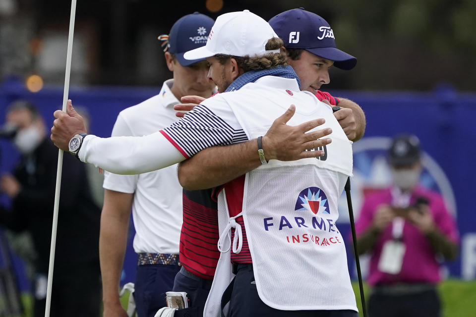 Patrick Reed, facing right, hugs his caddie, Kessler Karain, after putting on the 18th hole on the South Course to win the Farmers Insurance Open golf tournament at Torrey Pines, Sunday, Jan. 31, 2021, in San Diego. (AP Photo/Gregory Bull)