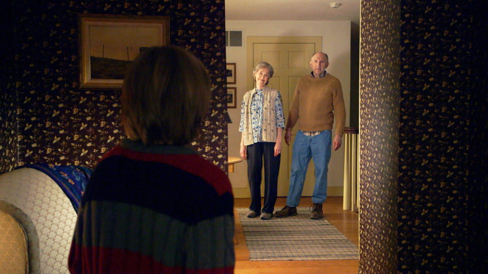 A young boy stands in front of an elderly couple