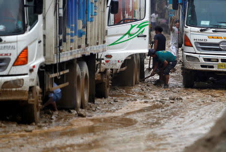 People clear mud from around the tyres of trucks at the Central Highway after a mudslide in Huarochiri, Lima, Peru, March 23, 2017. REUTERS/Guadalupe Pardo