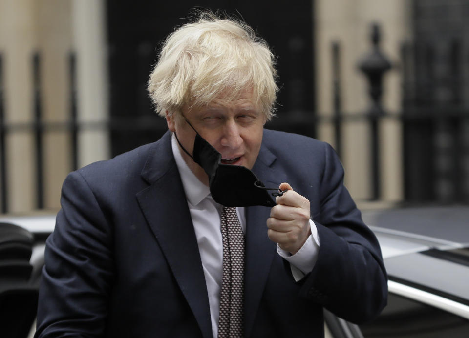 Britain's Prime Minister Boris Johnson takes his face mask off as he returns to10 Downing Street in London, Thursday, Nov. 26, 2020. Johnson leaves self-quarantine today after having close contact with a lawmaker who contracted the coronavirus in mid November. (AP Photo/Kirsty Wigglesworth)