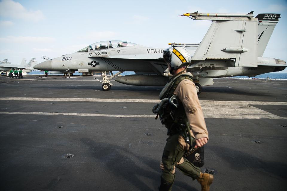 A pilot walks past an F/A-18 fighter jet on the deck of the USS Abraham Lincoln aircraft carrier in the Arabian Sea, Monday, June 3, 2019. The U.S. aircraft carrier the White House ordered to the Mideast over a perceived threat from Iran remains outside of the Persian Gulf amid efforts to de-escalate tensions between Tehran and Washington. (AP Photo/Jon Gambrell)