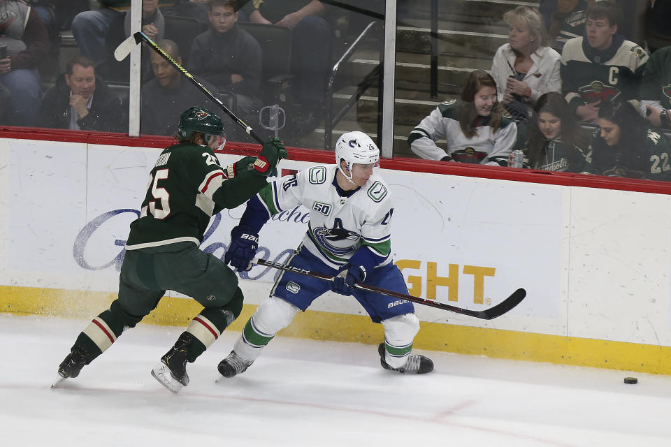 Minnesota Wild's Jonas Brodin, left, and Vancouver Canucks' Antoine Roussel, of France, go after the puck in the first period of an NHL hockey game Sunday, Jan. 12, 2020, in St. Paul, Minn. (AP Photo/Stacy Bengs)