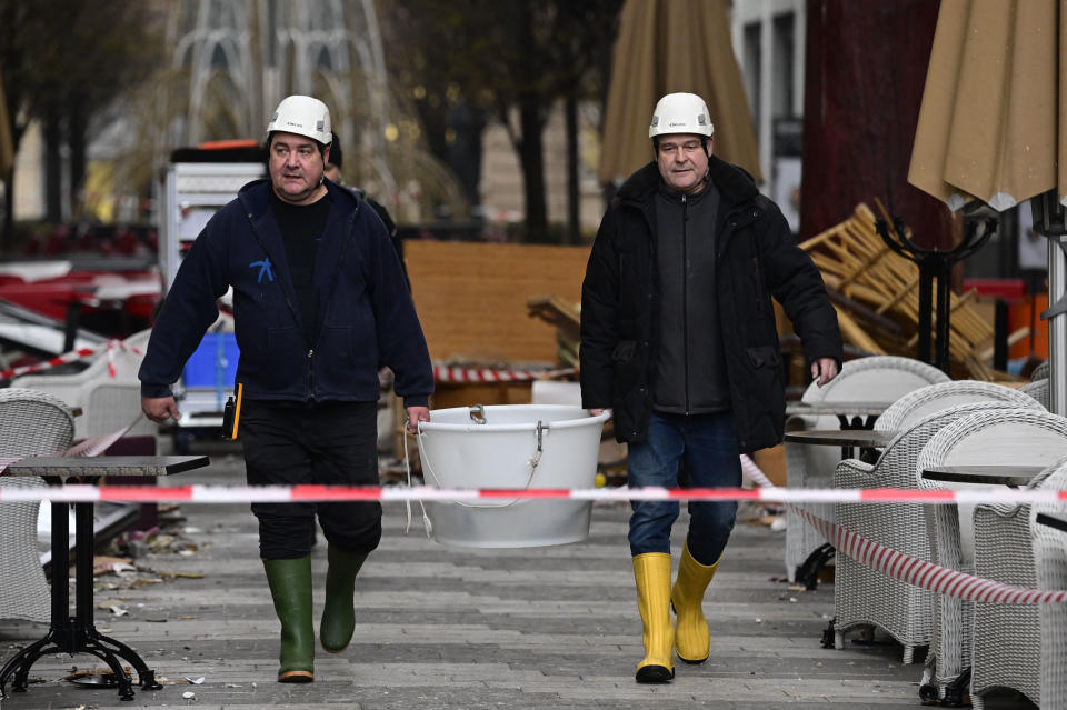 First responders evacuate live fish in a basin as they clean up the foyer of the Radisson Blu hotel after a huge aquarium located in the hotel's lobby burst on December 16, 2022 in Berlin. - The AquaDom aquarium has burst and the leaking water has forced the closure of a nearby street, police and firefighters said. Berlin police said on Twitter that as well as causing 