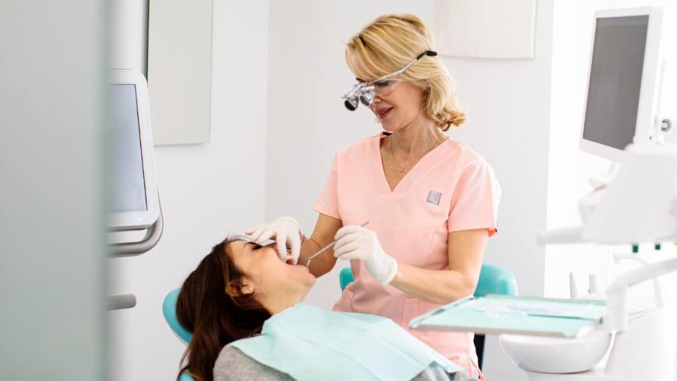 A female dentist examining a woman as she teaches her how to stop bleeding gums