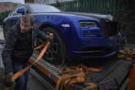 A man secures a luxury vehicle which was seized in a case against media influencer Andrew Tate, is towed away, on the outskirts of Bucharest, Romania, Saturday, Jan. 14, 2023. Prosecutors seized several luxury vehicles after Tate lost a second appeal this week at a Bucharest court, where he challenged the seizure of assets in the late December raids, including properties, land, and a fleet of luxury cars. More than 10 properties and land owned by companies registered to the Tate brothers have also been seized so far. (AP Photo/Alexandru Dobre)