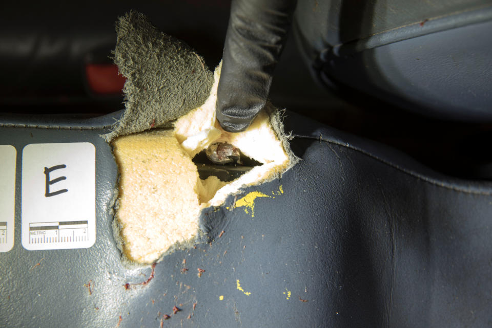 An investigator lifts fabric to show a bullet lodged in the car of Philando Castile.&nbsp;