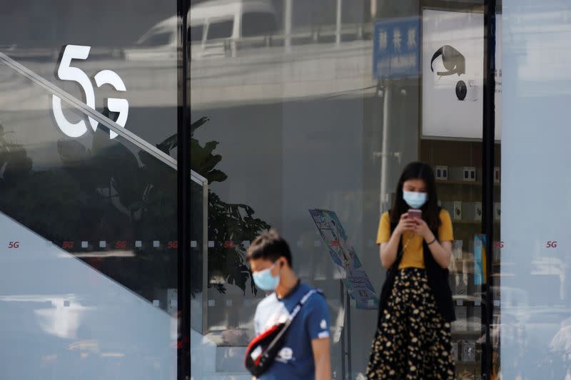 Woman uses a mobile phone outside a Huawei store with a 5G sign in Beijing