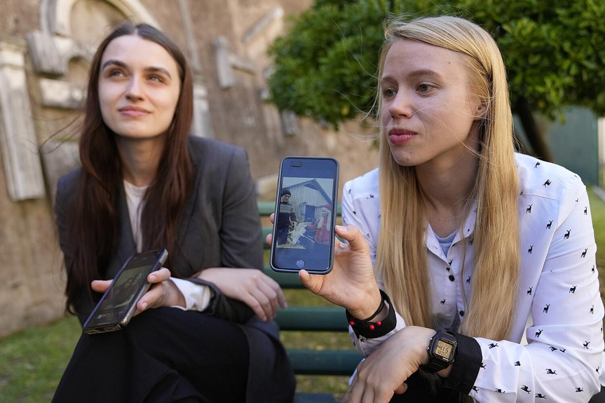 Kateryna Prokopenko, wife of Denys Prokopenko, commander of the Azov regiment, right, and Yulia Fedosiuk, wife of Arseny Fedosiuk, another member of Azov regiment show photos on their phones of their husbands during an interview with the Associated Press, in Rome, . Two Ukrainian women whose husbands are defending a besieged steel plant in the southern city of Mariupol are calling for any evacuation of civilians to also include soldiers. They say the troops stand to be tortured and killed if left behind and captured by Russian forces