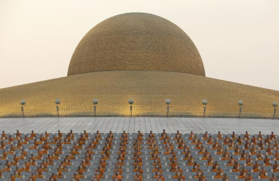 FILE - In this Feb. 22, 2016, file photo, Buddhist monks pray at Wat Dhammakaya temple to participate in Makha Bucha Day ceremonies in Pathum Thani, Thailand. A gilded golden dome glimmers at Wat Dhammakaya's center, appearing to hover UFO-like over meditation grounds large enough to accommodate millions of devotees in 30 countries. (AP Photo/Sakchai Lalit, File)