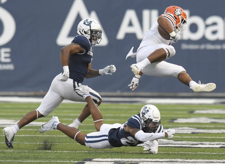 Idaho State running back Raiden Hunter (5) leaps over Utah State cornerback Gabriel Bryan as safety Anthony Switzer helps defend during the first half of an NCAA college football game Saturday, Sept. 9, 2023, in Logan, Utah. | Eli Lucero/The Herald Journal via AP