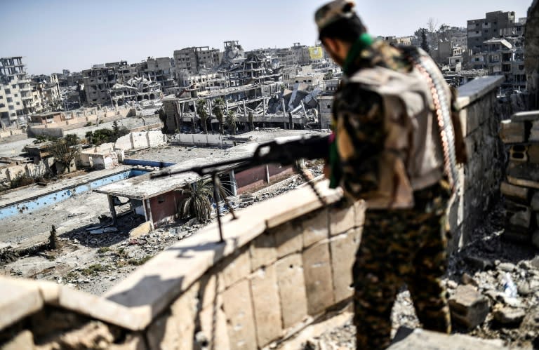 A fighter of the Syrian Democratic Forces (SDF) stands guard on a rooftop in Raqa on October 20, 2017