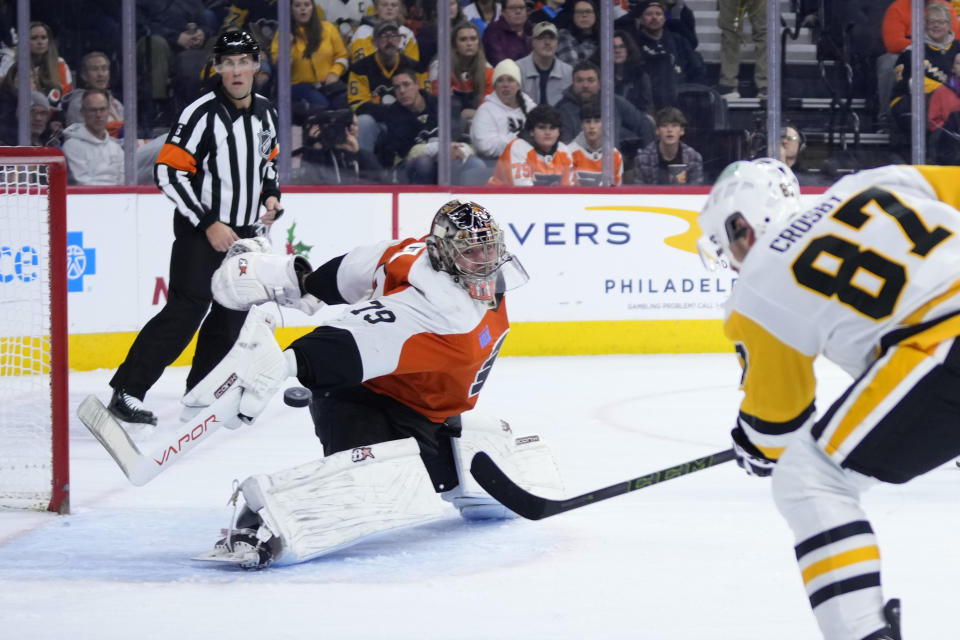 Philadelphia Flyers' Carter Hart, left, cannot stop a goal by Pittsburgh Penguins' Sidney Crosby during the first period of an NHL hockey game, Monday, Dec. 4, 2023, in Philadelphia. (AP Photo/Matt Slocum)