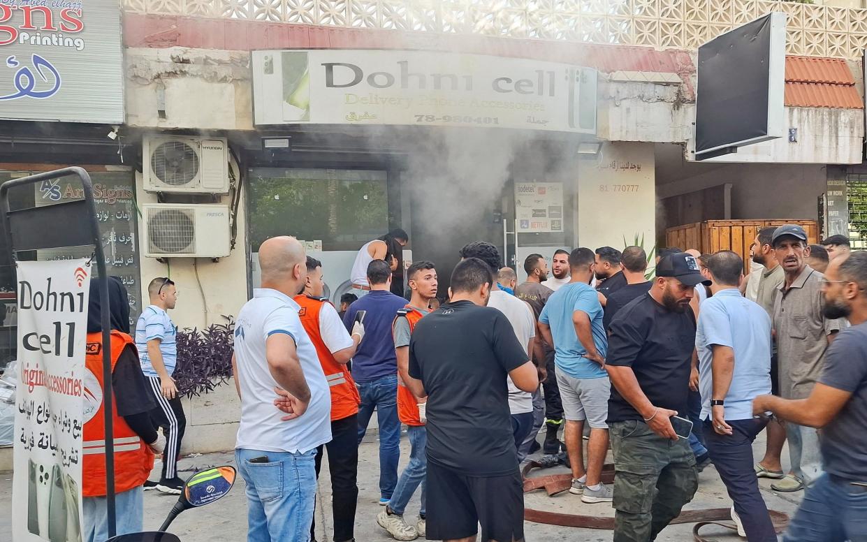 People gather as smoke rises from a mobile shop