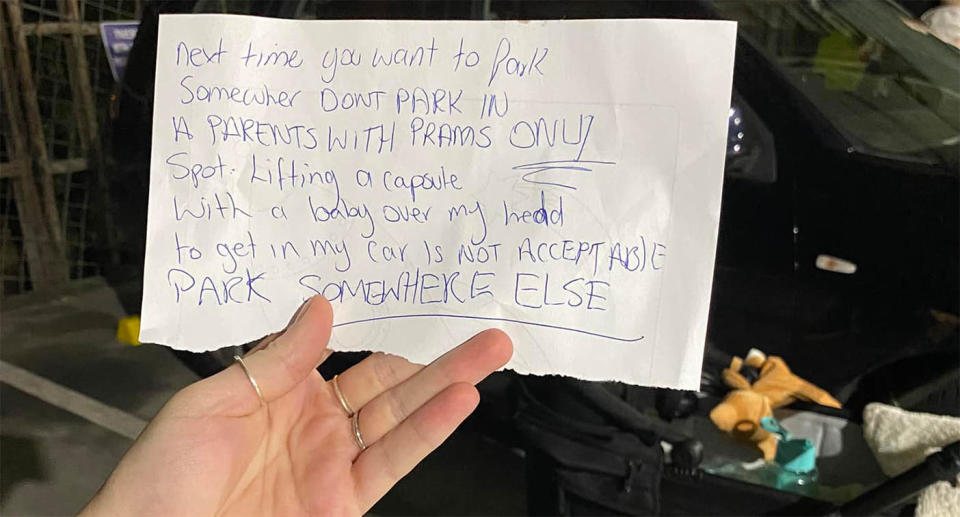 A woman holds up an angry note that was left on her car.