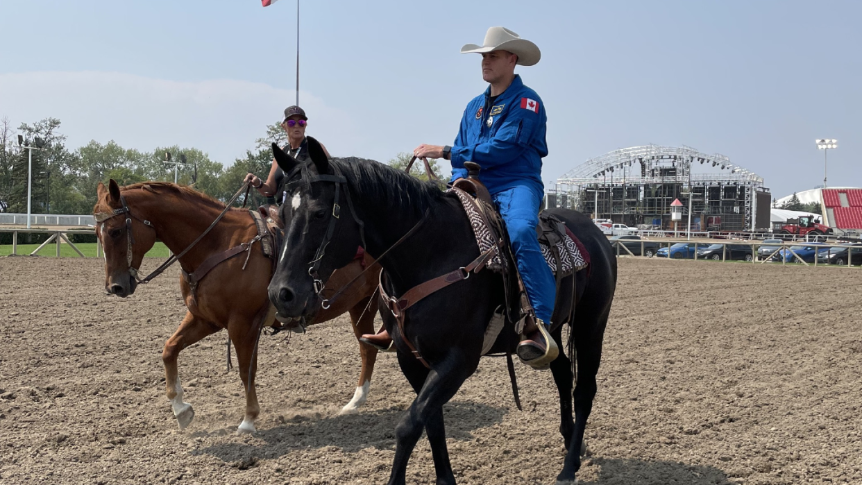  artemis 2 astronaut jeremy hansen on board a horse in a flight suit. a ring is behind him 