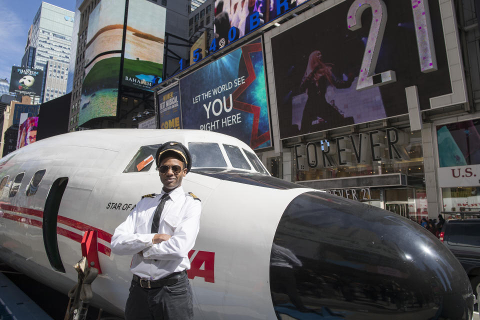 An actor dressed as a pilot from the 1960s and 70s poses for a photo next to a Lockheed Constellation L-1649A Starliner, known as the "Connie, is parked in New York's Times Square during a promotional event, Saturday, March 23, 2019, in New York. The vintage commercial airplane will serve as the cocktail lounge outside the TWA Hotel at JFK airport, a hotel that promises to bring back "the magic of the Jet Age." (AP Photo/Mary Altaffer)