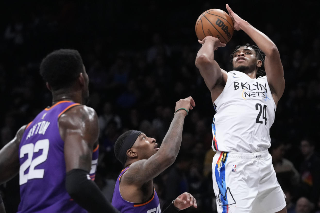 Brooklyn Nets guard Cam Thomas (24) shoots a three-point basket past Phoenix Suns center Deandre Ayton (22) and forward Torrey Craig during the first half of an NBA basketball game, Tuesday, Feb. 7, 2023, in New York. (AP Photo/Mary Altaffer)