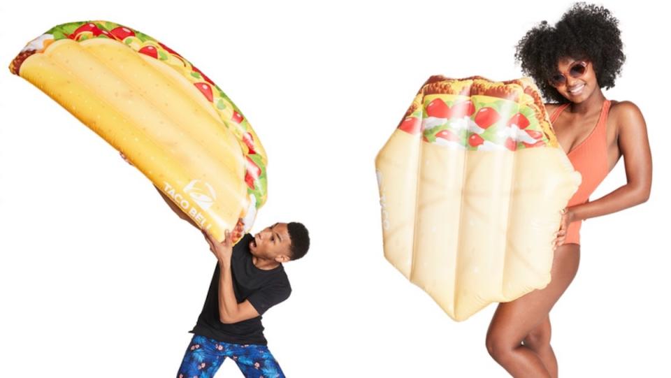 A man pretends to eat a pool float shaped like a taco and a woman in a bathing suit and sunglasses holds a crunchwrap supreme Taco Bell pool float