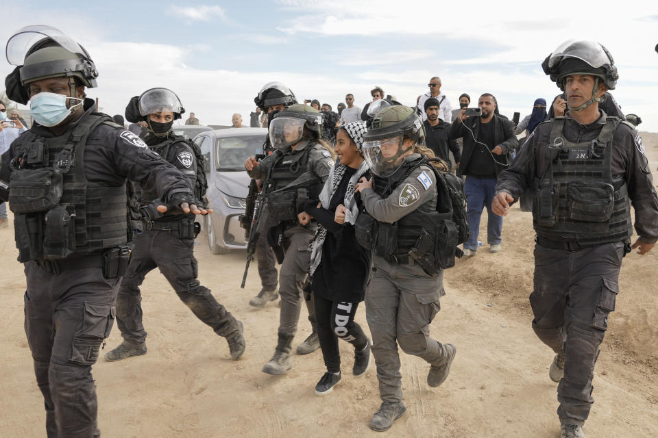 Israeli security forces detain a Bedouin youth during a protest against tree-planting by the Jewish National Fund on disputed land near beduin village of al-Atrash at the Negev desert, southern Israel, Wednesday, Jan. 12, 2022. The conflict in southern Israel, which is home to Bedouin villages unrecognized by the state, has divided the Israeli government with Foreign Minister Yair Lapid calling for halting the tree-planting while the Islamist Ra'am party has threatened to withhold its votes in parliament in protest. (AP Photo/Mahmoud Illean)