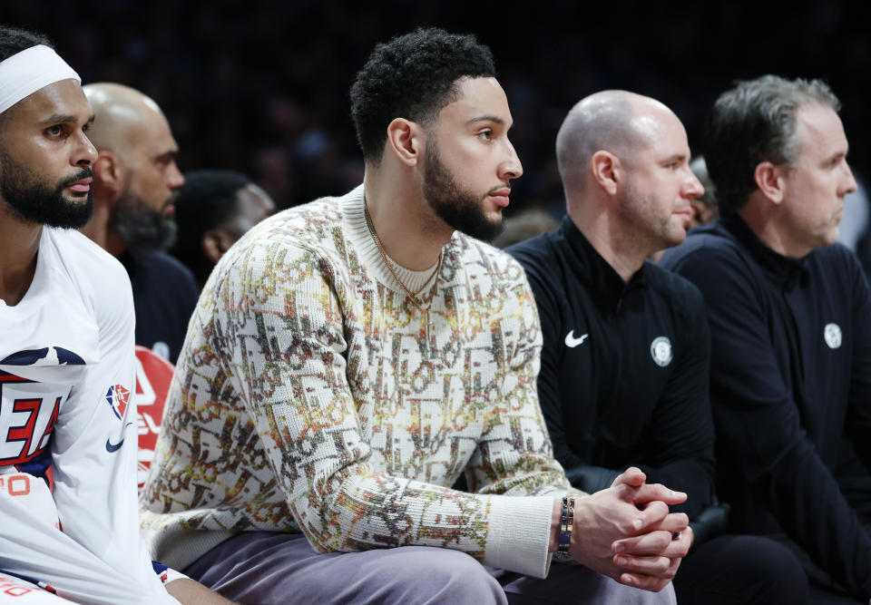 Pictured centre, Ben Simmons watches on during an NBA game featuring his Brooklyn Nets.