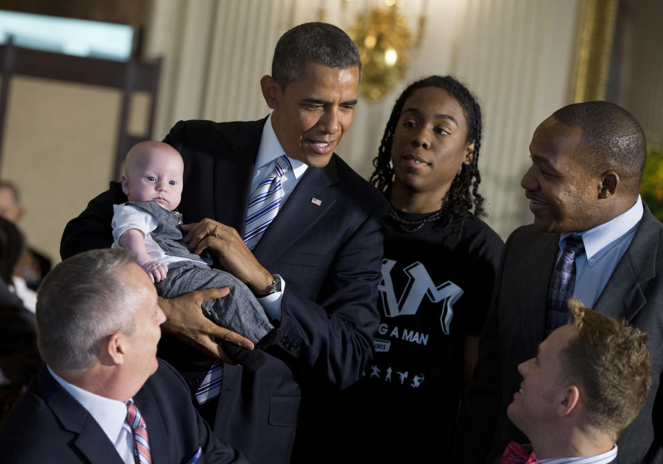 President Barack Obama holds a child a he mingles in the State Dining Room of the White House in Washington, Friday, June 14, 2013, where he hosted a Father's Day luncheon. Obama hosted fathers and their children as well as students and leaders from the Becoming a Man program at Hyde Park Academy in Chicago for the lunch. (AP Photo/Evan Vucci)