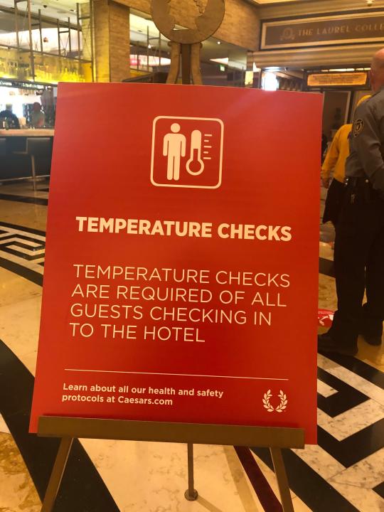 A sign in the lobby of Caesars Palace in Las Vegas announces the hotel's new temperature check policy.