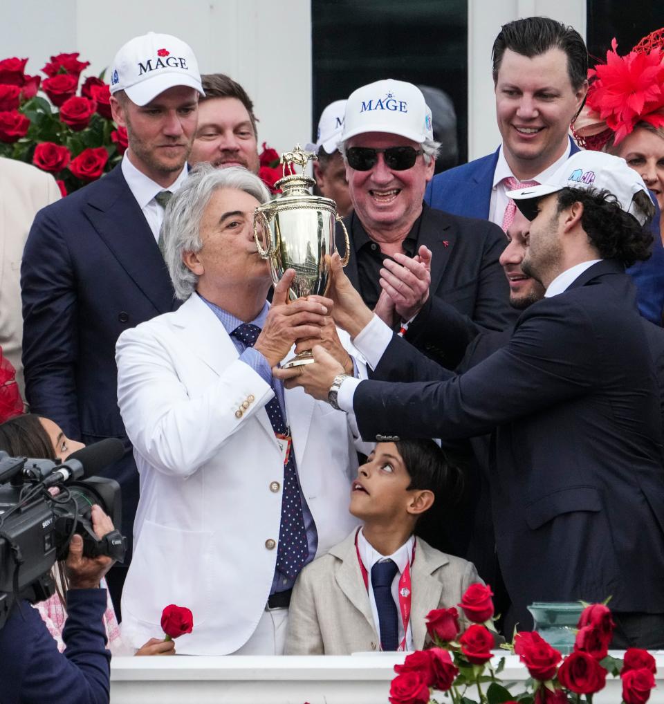 Owner/Trainer Gustavo Delgado kisses the Derby trophy as son Gustavo Delgado, Jr. holds it as well in the Winner's Circle after their horse Mage won the 149th Kentucky Derby Saturday at Churchill Downs in Louisville, Ky. May, 6, 2023.