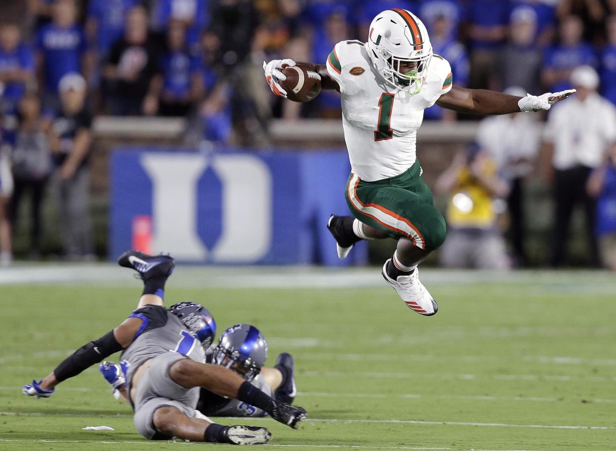 Miami’s Mark Walton, right, jumps over Duke’s Ben Humphreys and Bryon Fields Jr. during the first half of an NCAA college football game in Durham, N.C., Friday, Sept. 29, 2017. (AP Photo/Gerry Broome)