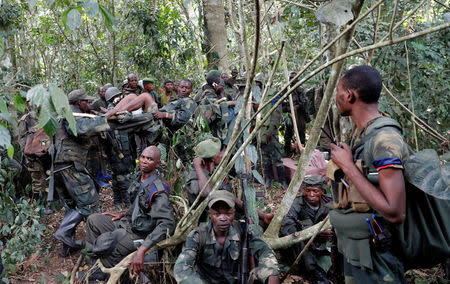 A wounded Congolese soldier from the Armed Forces of the Democratic Republic of Congo (FARDC) is carried by another soldier in the forest after the army took control of a ADF rebel camp, near the town of Kimbau, North Kivu Province, Democratic Republic of Congo, February 19, 2018. REUTERS/Goran Tomasevic/Files