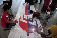 Visitors write on a banner carrying messages for the passengers of missing Malaysia Airlines flight MH370 at Kuala Lumpur International Airport (KLIA) in Sepang, outside Kuala Lumpur on March 16, 2014