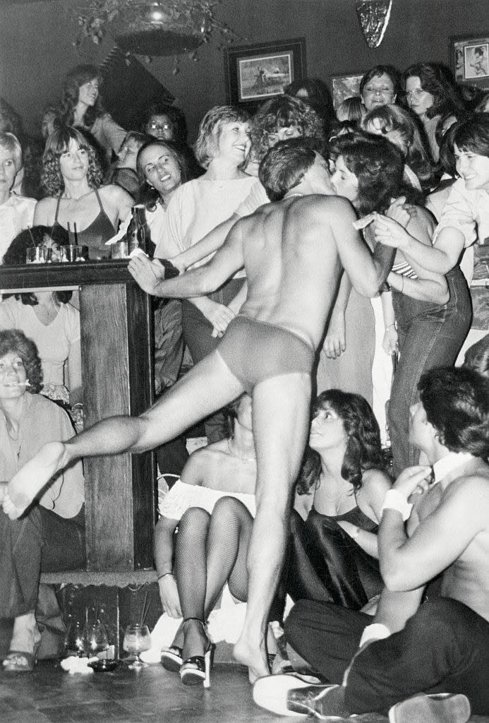 A Chippendales performing kissing a woman who's surrounded by other women in the club